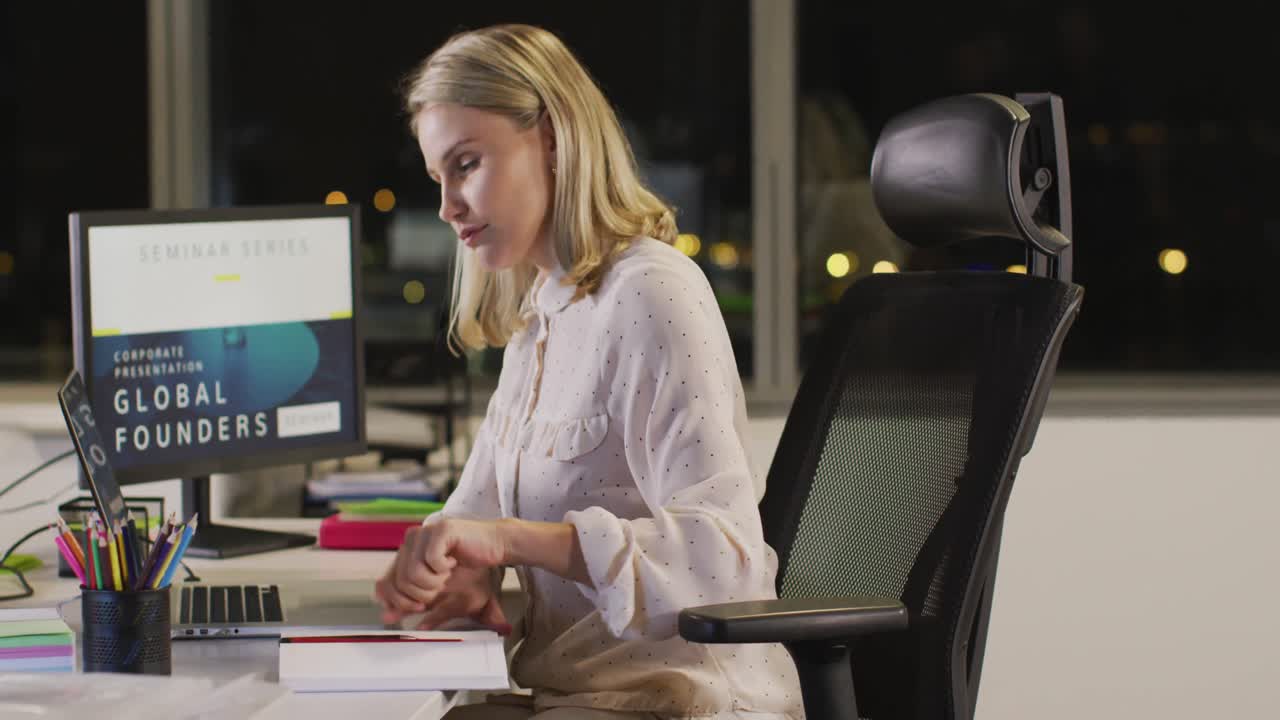 Donna d'affari professionista che prende appunti mentre utilizza un laptop in un ufficio moderno al rallentatore.