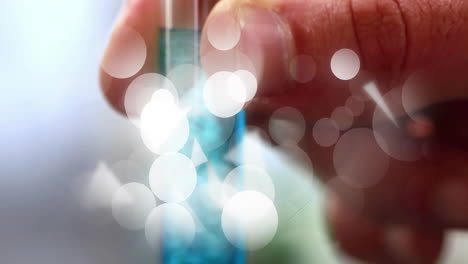 holding test tube with blue liquid, hand surrounded by glowing animation lights