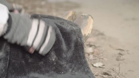 hands of homeless person wrapping feet in blanket