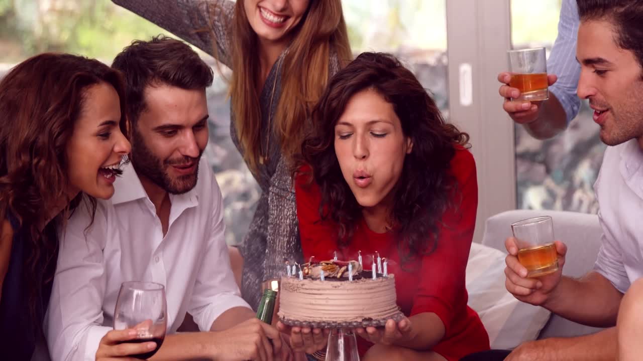mujer apagando una vela en su pastel de cumpleaños