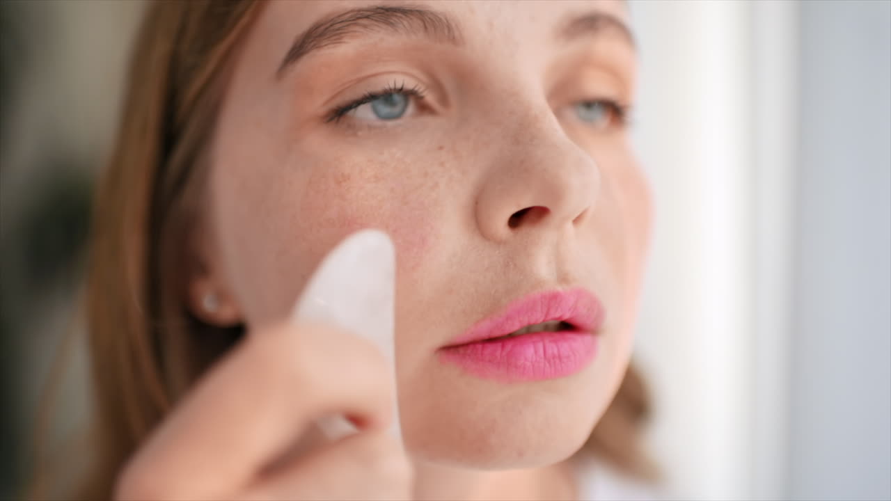 Woman using a gua sha for facial massage