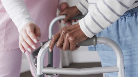 Caucasian-female-nurse-and-senior-african-american-woman-with-walking-frame,-copy-space,-slow-motion