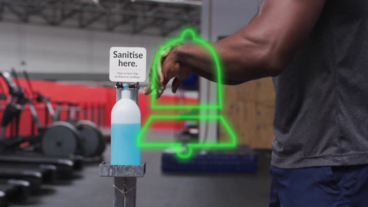 Person sanitizing hands with green bell animation over gym equipment in background