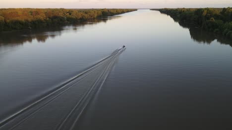 toma aérea de un bote de velocidad de crucero en el tranquilo río amazonas durante una puesta de sol épica