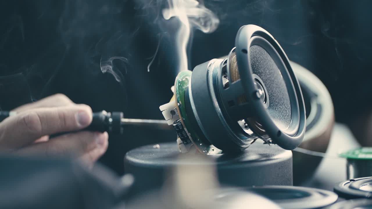 Close up of Worker carefully soldering audio circuit board for speaker production, industrial workshop environment, focus on precision and skill