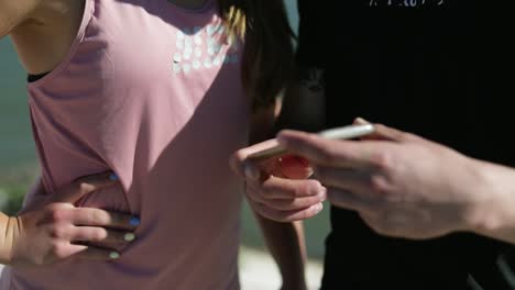 una foto recortada de dos personas con un teléfono inteligente durante un día ventoso.