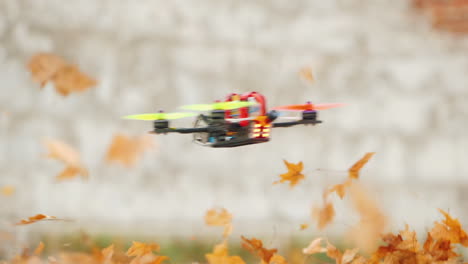 el dron vuela rápido y bajo sobre el suelo levantando hojas del suelo en el viento