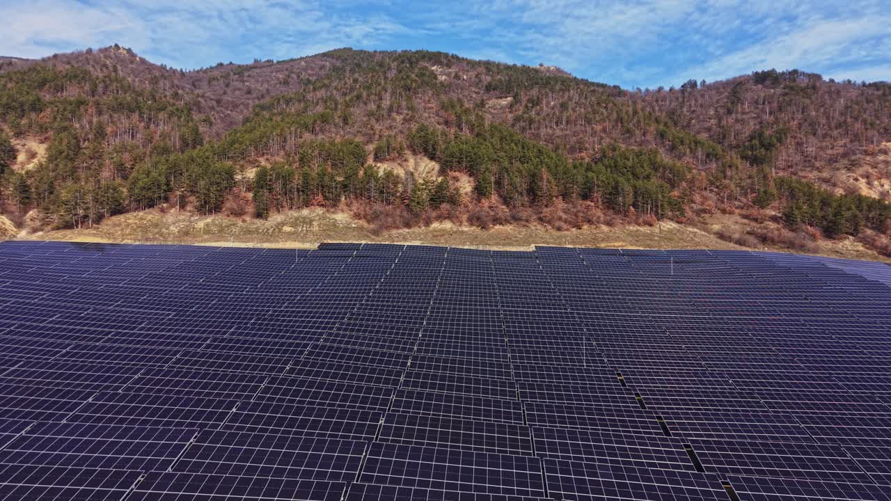 Solpaneler genererer energi på en solskinsdag tæt på en bjergkæde