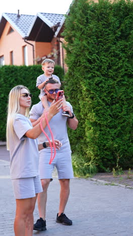family fun in summer sun. a family engages in a joyful moment outside, with a child on a father's shoulders, capturing memories together