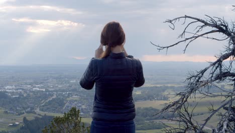 woman looking over the green valley below on a summer day