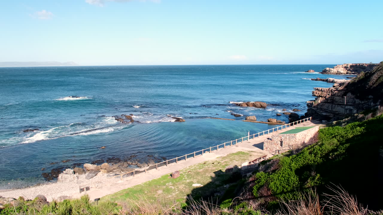 High angle riser reveal of scenic marine tide pool on Hermanus coastline