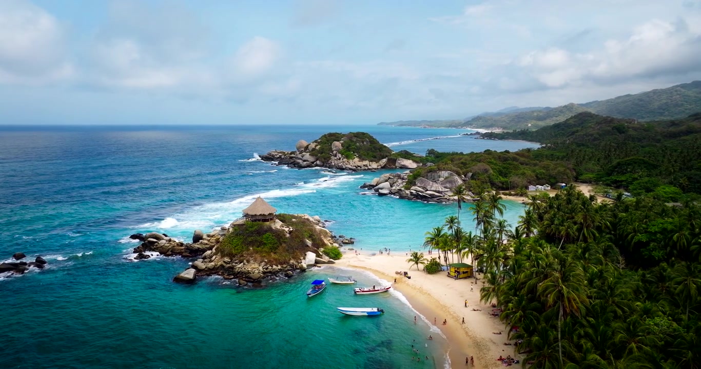 Capanna con tetto di paglia su una roccia costiera accanto a una spiaggia sabbiosa e a una giungla verde tropicale a Cabo San Juan de Guia nel Parco Nazionale Tayrona, Colombia