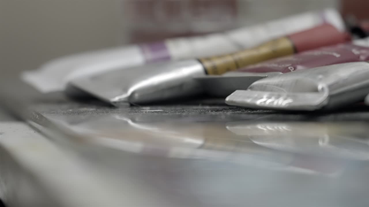 Extreme close up of silver paint tubes on a reflective glass palettes