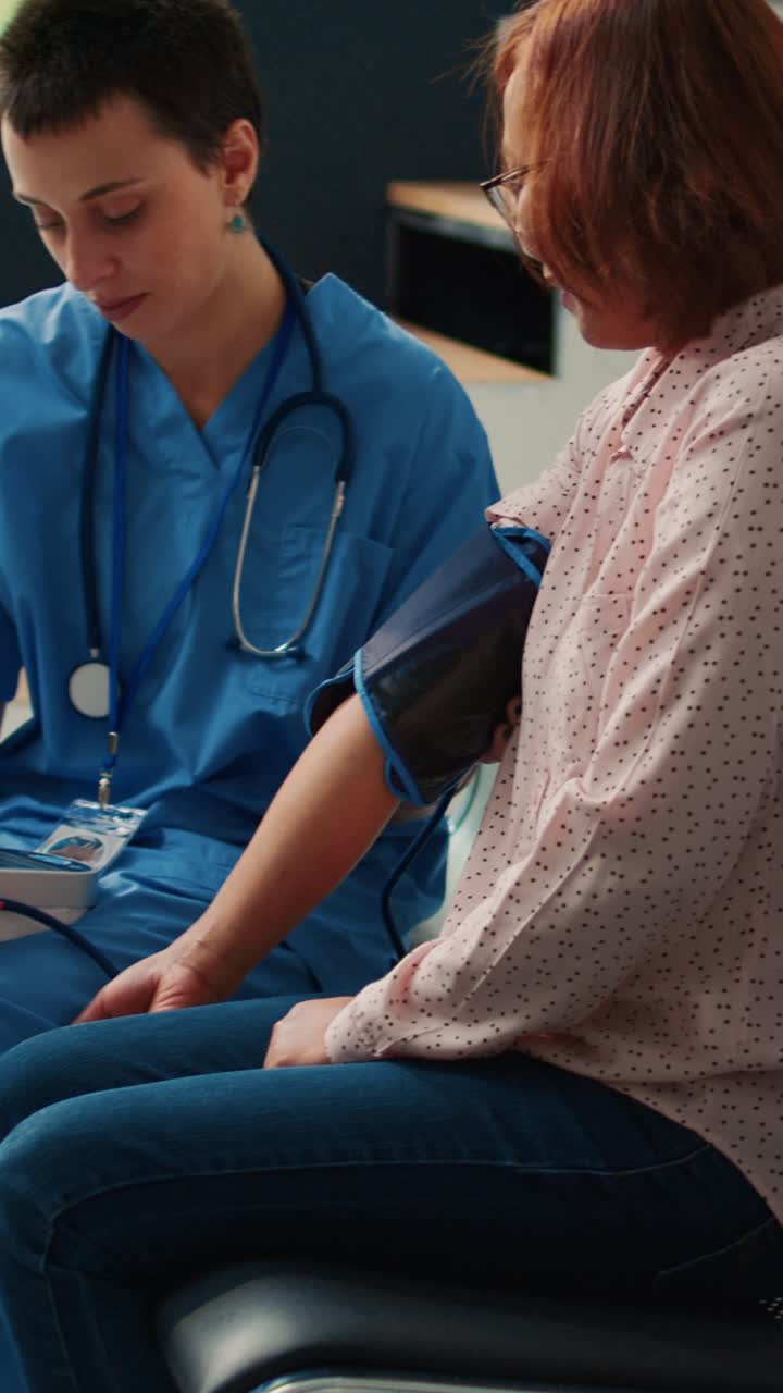 Vertical video: Nurse doing cardiology exam with tonometer to measure hypertension