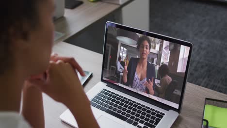 African-american-businesswoman-sitting-at-desk-using-laptop-having-video-call-with-female-colleague