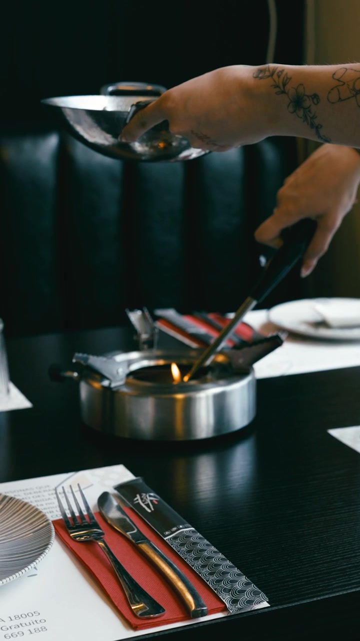 Chef Preparing Stir-Fry in a Wok at a Restaurant Table