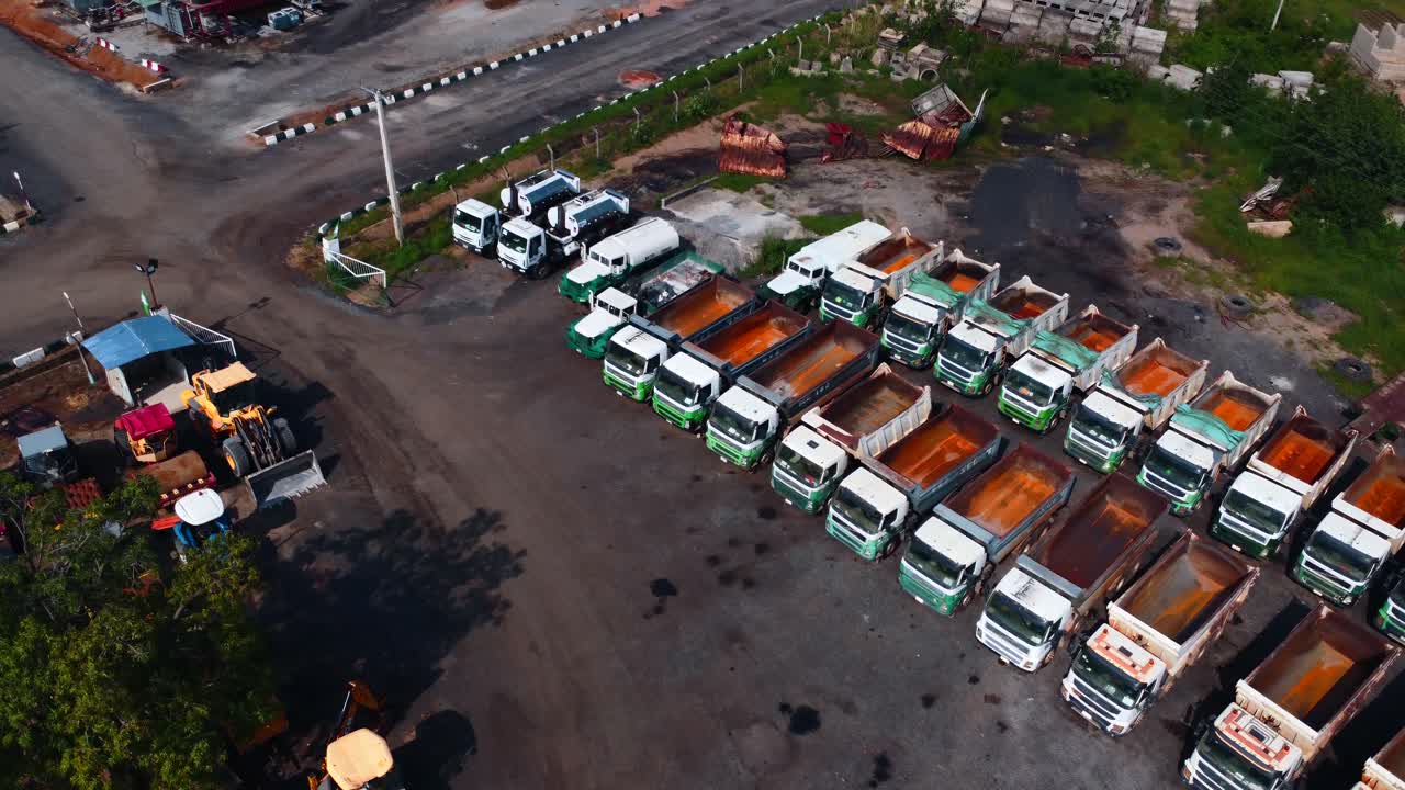 Aerial footage of dump trucks, gravel piles, and machinery at Nigerian work site. Abuja, Africa