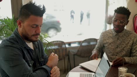 Serious multiethnic freelancers discussing work in cafe