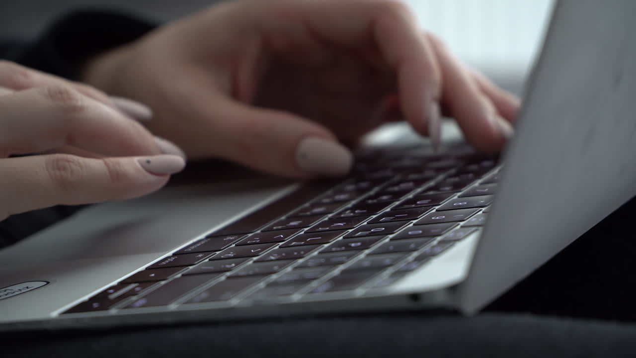 Kvindelige hænder trykker på tasterne på et MacBook-tastatur med russisk layout
