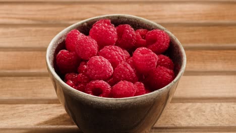 raspberries in a bowl on a wooden table