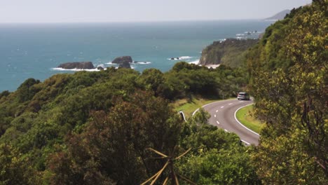 Car-driving-on-a-winding-coastal-highway-through-the-jungle