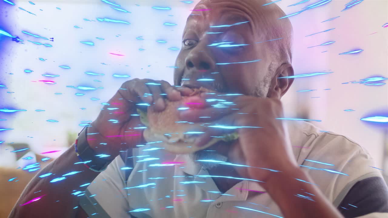 Senior man lifting sandwich to mouth, eating at home, blue-pink streaks overlaying face for food