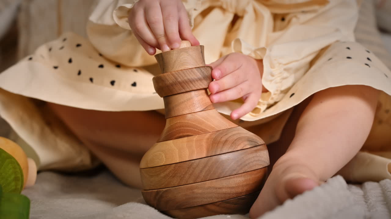 Little girl's hands playing with a wooden stacking jug. Ecological and sustainability concept