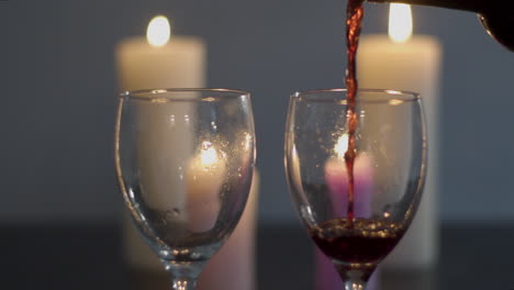 dos copas de vino tinto que se vierte en la mesa de la cena a la luz de las velas