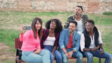 diverse group of friends taking a selfie on a park bench