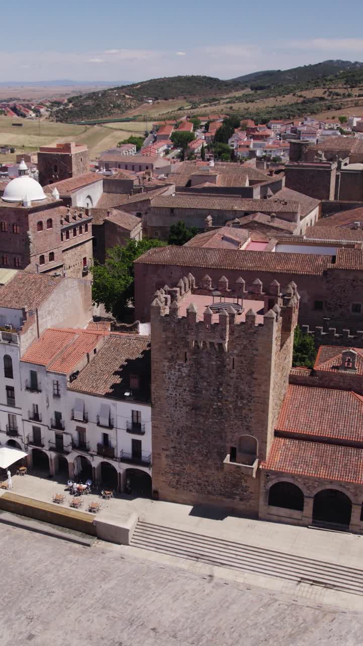 Órbita aérea vertical que muestra la icónica Torre de Bujaco y la Plaza Mayor dentro del casco histórico de Cáceres, España
