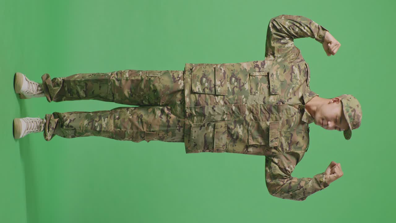Full Body Of Asian Man Soldier Smiling And Flexing His Bicep While Standing In The Green Screen Background Studio