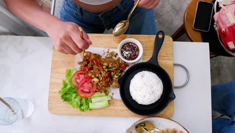 person eating crispy pork with chili and rice