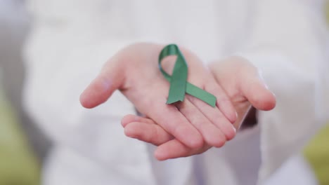 Cerca-De-Una-Feliz-Doctora-Caucásica-Sosteniendo-Una-Cinta-Verde-De-Sensibilización