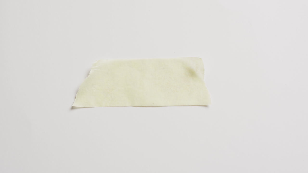 Video of close up of torn piece of yellow paper on white background