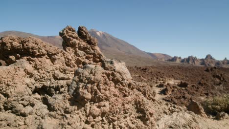 Mount-Pico-del-Teide-and-Los-Roques-de-Garcia-revealed-behind-volcanic-rock,-Teide-National-Park-in-Tenerife,-Canary-Islands-in-spring