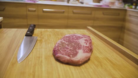 a4 wagyu beef and a kitchen knife on a wooden chopping board