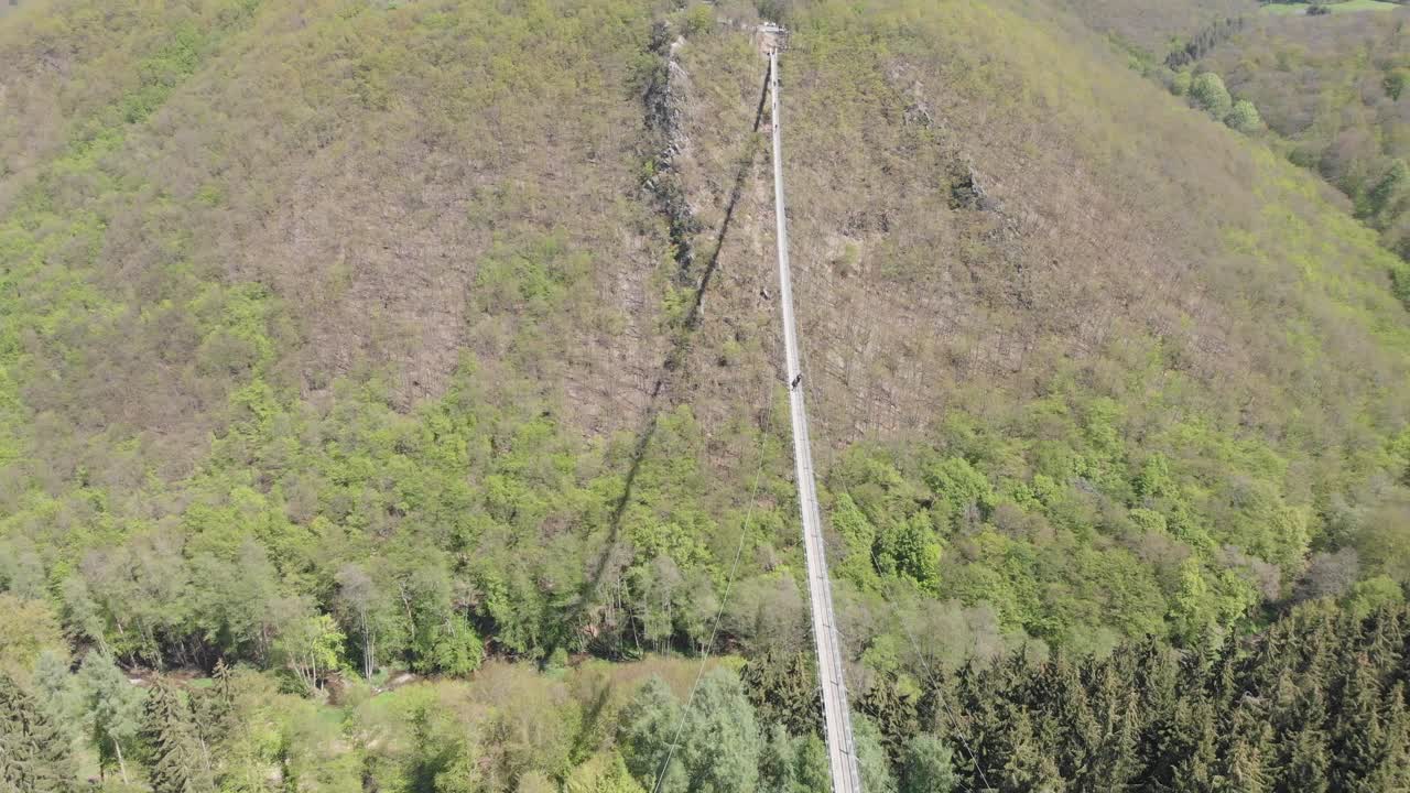 наклонный кадр над очень длинным вантовым мостом, когда люди переходят через долину