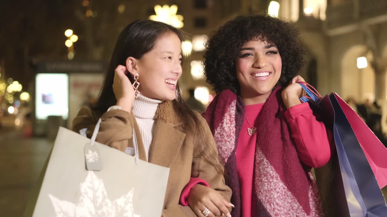 Two women shopping in the city at night