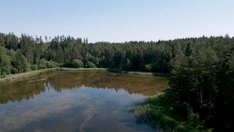 Drone-flight-aerial-bird-flyover-a-tiny-lake-in-Mazury-Region-in-northern-and-northeastern-Poland,-famous-for-its-2,000-lakes,-part-of-the-Warmian-Masurian-Voivodeship---June-2022