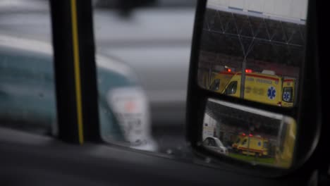 vista de una ambulancia con luces intermitentes vista a través de un espejo retrovisor