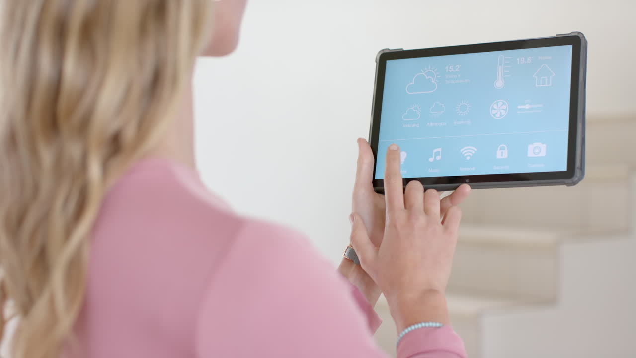 feliz mujer caucásica usando tableta con hogar inteligente en la pantalla en casa, cámara lenta