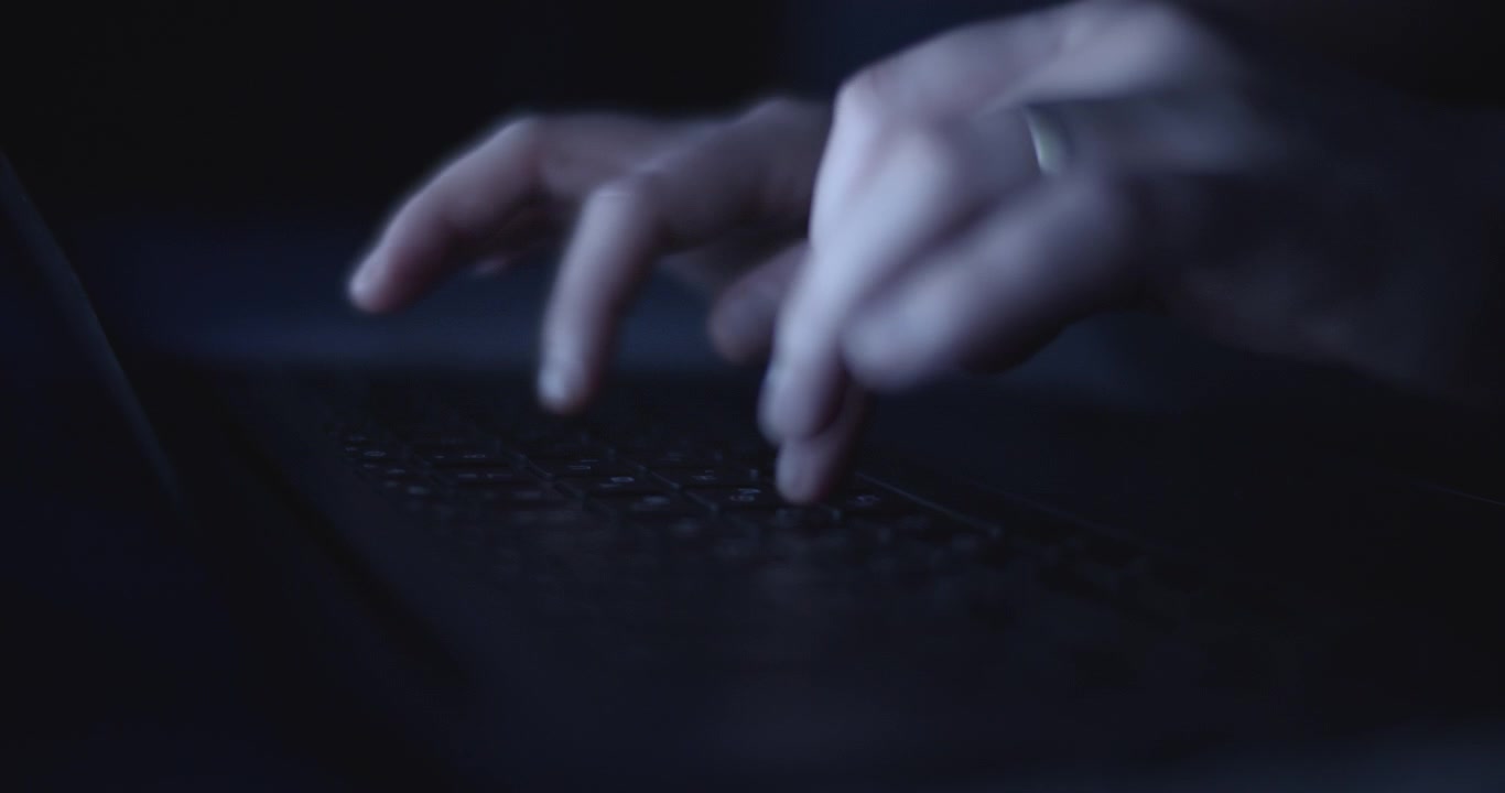 Mani che digitano su una tastiera di notte