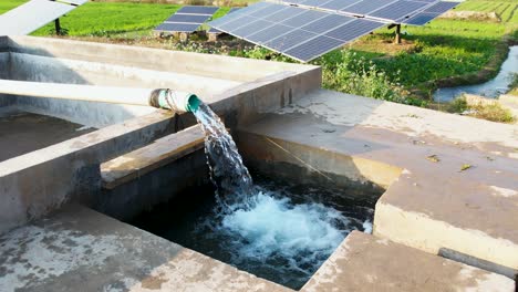 water flows from a solar-powered tubewell beside solar panels used for irrigating nearby farmland. punjab, pakistan
