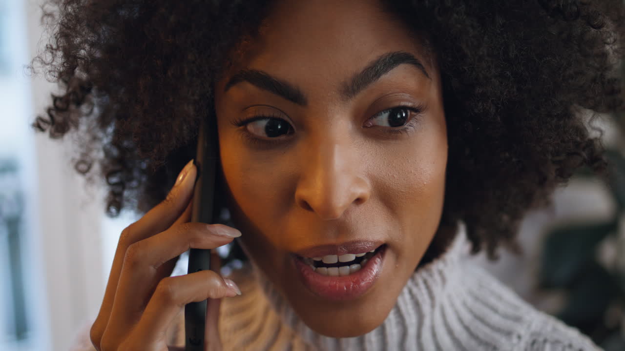 Positive woman calling smartphone at home close up. African lady sharing secrets