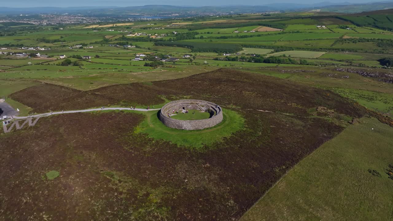 Grianan of Aileach, County Donegal, Ireland, June 2023. Drone counter clockwise orbit as visitors explore the Iconic Gaelic Ringfort with Derry City and Lough Swilly in the distance on a sunny day.