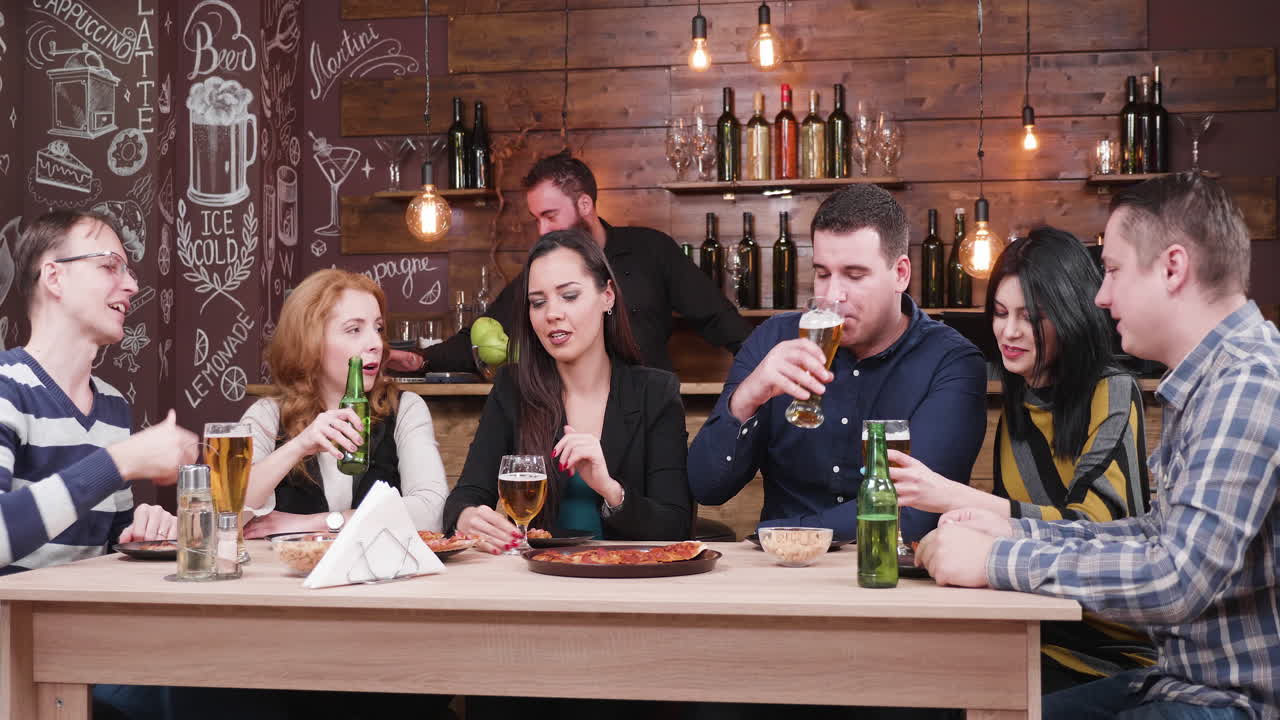 People enjoying a pizza and beverages at the bar