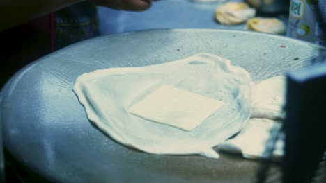 4k cinematic cooking footage of a thai chef preparing a traditionnal thai dessert called roti in a street market in thailand