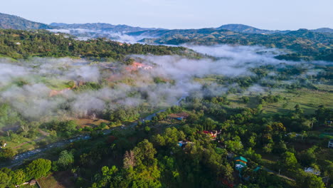 Stunning-aerial-view-of-the-mountains-with-dense-fog-and-a-river,-winter-weather-in-the-caribbean