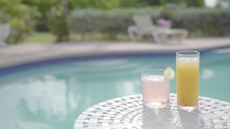 Zwei-Gesunde,-Natürliche-Bio-Saft-Cocktails-Mit-Swimmingpool-Im-Hintergrund