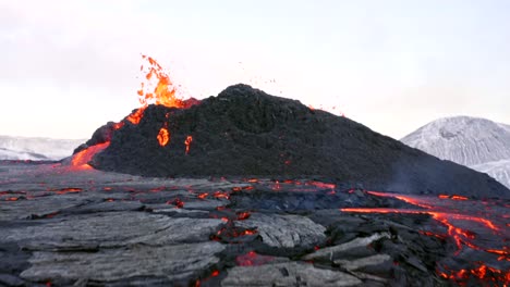 A-4K-drone-captures-cinematic-aerial-footage-of-a-volcano-rapidly-expelling-lava,-followed-by-a-slow-motion-cascade-down-the-base-of-the-peak-in-Iceland